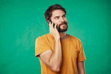 man with mobile phone and yellow t-shirt on green background cropped view