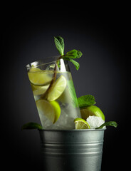 Mojito cocktail with ice, lime, and mint in a bucket with ice.