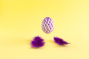 The creative Easter concept made of purple fins and natural eggs with purple stickers levitates above on a yellow background. Minimal holiday or spring concept.