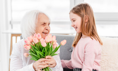 Fototapeta na wymiar Grandaughter gives flowers to grandmother