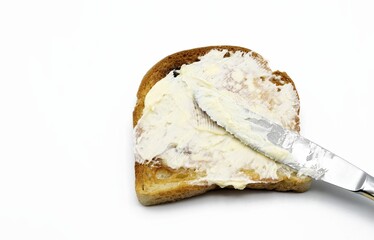 Spreading butter with a knife on toast isolated on white background