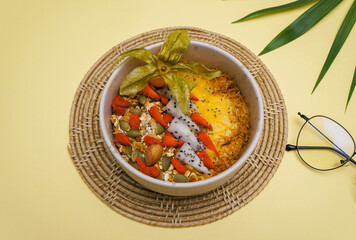 Healthy pineapple, mango and strawberry smoothie bowl with granola, seeds , almond fresh strawberries and fresh apple in White ceramic bowl.detox, vegetarian, vegan food concept