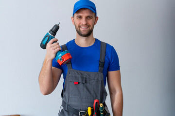 Uniformed maintenance worker holds a screwdriver and looks at the camera. Handyman wearing a tool...