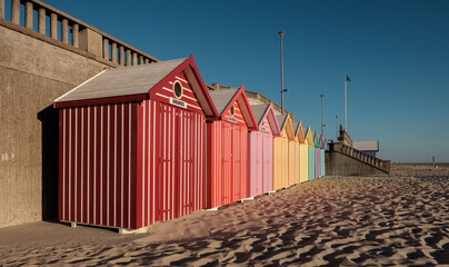 Beach cabins with vibrant colors on the French coast. Perspective view. - obrazy, fototapety, plakaty