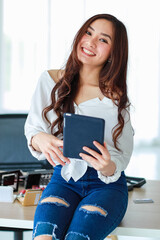 Selective focus on phone, female vlogger, influencer, or online seller holding tablet computer and look at camera ready to record cosmetic reviewing video. Online marketing concept.