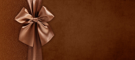 gift card with bright and shiny ribbon bow isolated on brown grunge background, top view and copy...