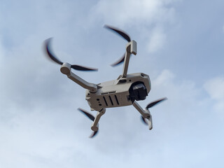 Grey drone with camera flying in the air outdoors. Little drone flying outside in sky.