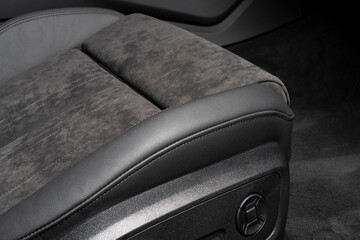 Modern luxury car black leather and alcantara interior. Part of black perforated leather car seat details with white stitching. Interior of prestige car. Comfortable perforated leather seats.