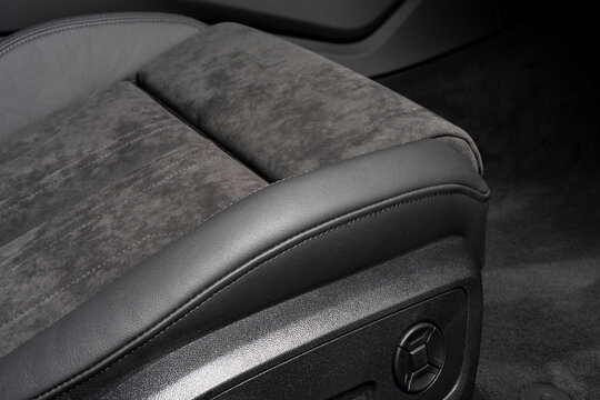 Modern luxury car black leather and alcantara interior. Part of black perforated leather car seat details with white stitching. Interior of prestige car. Comfortable perforated leather seats.