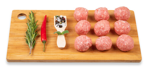 Raw meat balls on a chopping board. Rosemary, chili pepper, spices. White background.