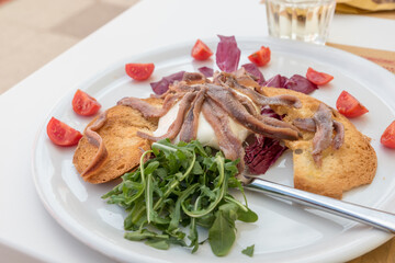 Burrata with anchovies, rocket and tomatoes