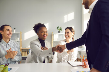 Handshake in office meeting. Happy thankful multiracial multiethnic colleagues shaking hands....
