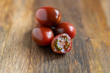 dark red brown tomato and whole vegetables on wooden background