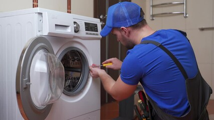 Working man plumber repairs a washing machine in home. Washing machine installation or repair. plumber connecting appliance