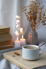 A cup of coffee, books, a bouquet of flowers and candles on the table. Composition in brown-beige tones. Stylish still life, blog life concept