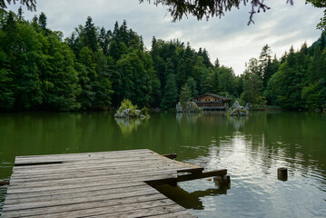 Wooden pier on a lake with a log house in the background in Austria