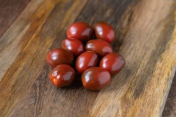 dark red tomato sprinkled on a brown wooden background