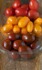 vertical set of cherry tomatoes red, yellow and black on a wooden background