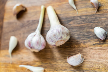 head of fresh garlic lies in the center of the frame of cloves on a wooden background