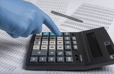 Hand in gloves on calculator calculating budget and expenses