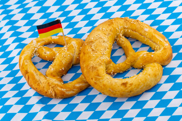 two fresh baked pretzels traditional snack for beer, Oktoberfest holiday symbol on white and blue rhombus pattern background