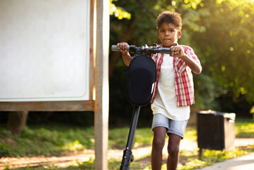 African American little boy riding electric scooter.