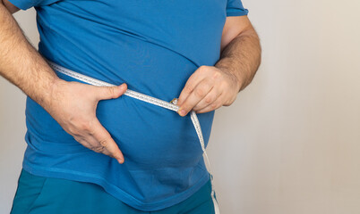 man measures the size of the abdomen with a centimeter measuring tape