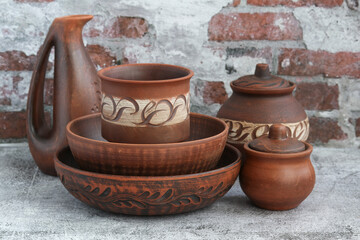 Set of ceramic utensils on a brick wall background.