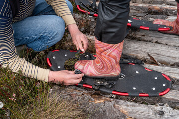 Tourists' feet, shod in rubber boots with special devices for walking in the swamp. One tourist...