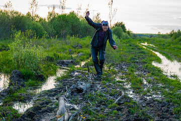 Woman hiker in the spring visits the swamps. Due to the spring flood, it is difficult to walk on a dirt road.