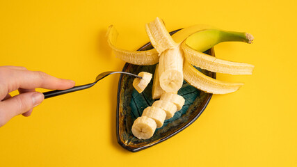 Cute breakfast for children, banana cut on a plate. Freshly sliced bananas on a yellow background