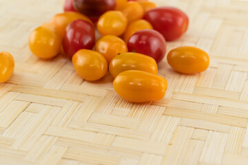 yellow cherry tomato and red closeup on a light wooden background