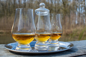 Tasting glasses of scotch whisky strong drink on old outdoor wooden table