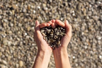 The girl's hands hold a handful of stones in the form of a heart