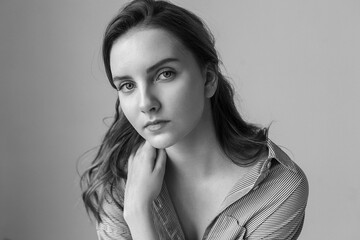 cute young pretty woman with long hair in shirt posing on gray background