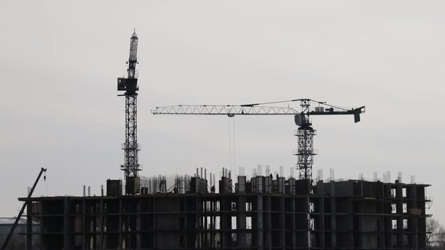 Time lapse of construction cranes and workers silhouettes