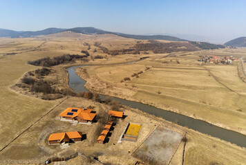Curving dirty Olt river at springtime near empty swimming pool and weekend cottages in...
