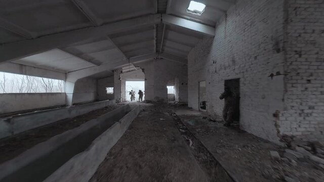 Group of people in masks and military uniforms are engaged in airsoft in an abandoned building. FPV drone shooting