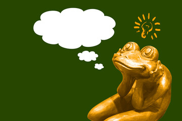 Golden frog statue dreaming about something with light bubble and thought bubbles for your text on green background,