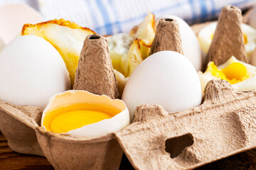 eggs in a cardboard box on the table some eggs are whole others are in different degrees of readiness