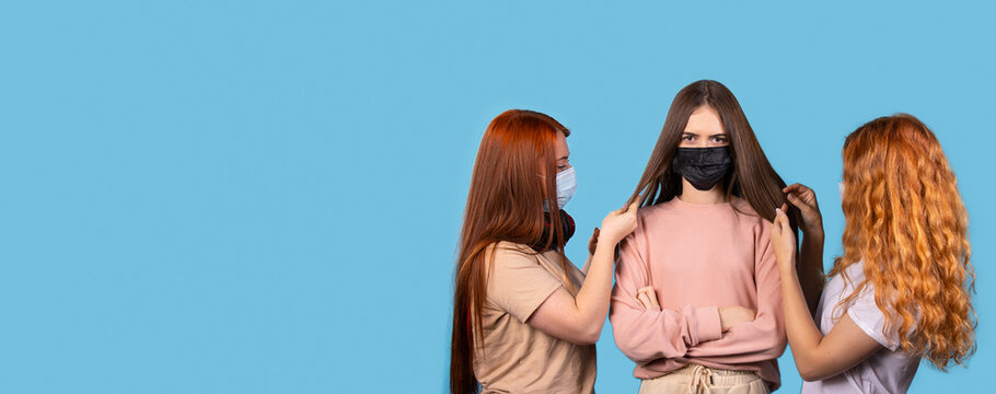 Banner,long format. Three young female friends with long hair and protective masks against the spread of covid 19. Studio photo with side advertising space.