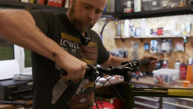 A male bike mechanic fits new bar end stoppers in a workshop.