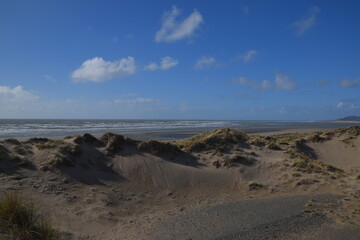 the sand dunes of ynyslas beach with the sky clear and blue