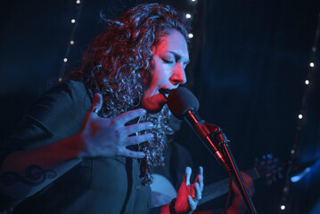 Curly hair woman performing music show with microphone. Rock pop female star singer performer with...