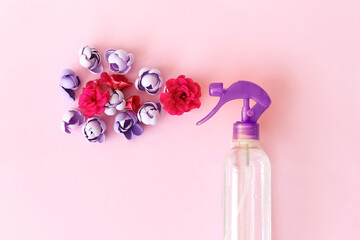 Spray air freshener with flowers on a pink background.