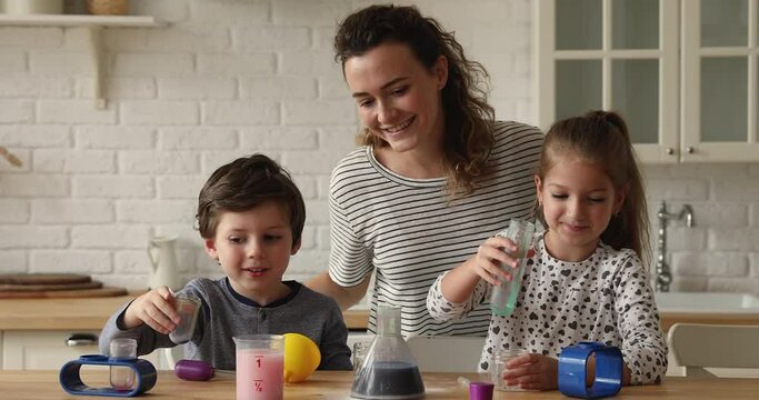 Young mother and kids little scientists play chemistry kit in kitchen, family make funny scientific experiment, having fun together at home on weekend. Learning through play, hobby, education concept
