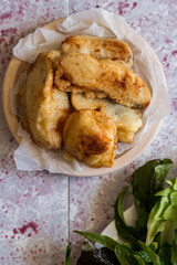 Fried battered cod with salad on the pink background.