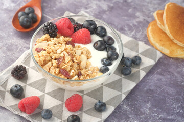 Granola with yogurt and berries in bowl on black background 
