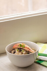 Ochazuke: tyical japanese dish made with white rice, grilled fish, seaweed and sesame seed. White bowl, green towel, grey background