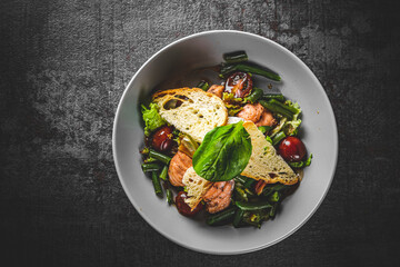 Green Bean Salad with Boiled Eggs, Salmon, Tomatoes and Arugula in a bowl on Dark grey black slate background